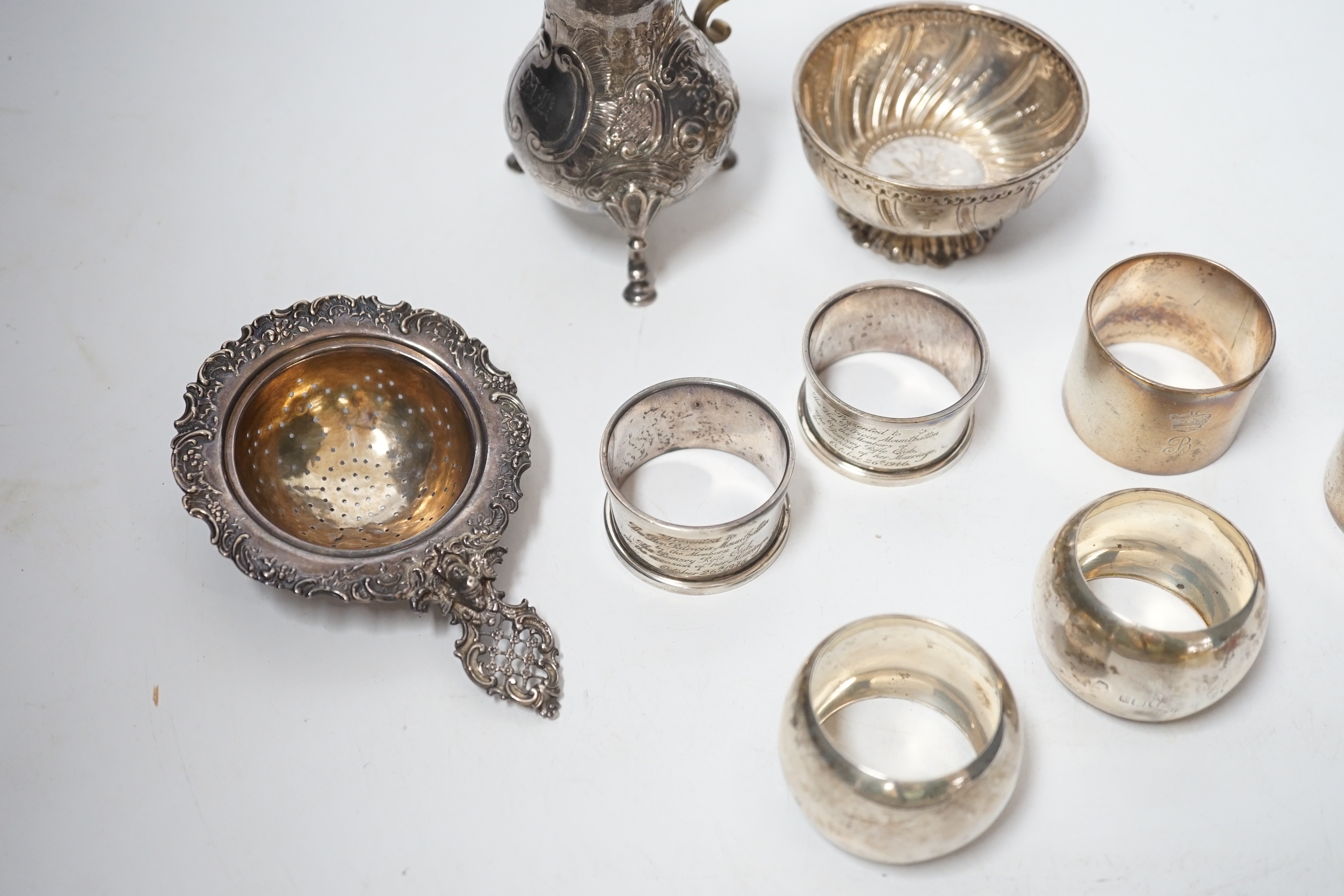 Sundry silver including six silver napkin rings, an 800 standard tea strainer and a white metal bowl and cream jug.